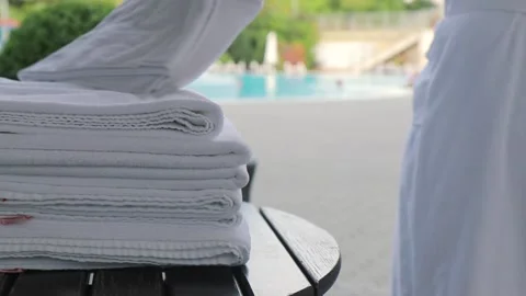 Man in a white bathrobe takes a white towel and goes to swim in the hotel pool Video stock 150268232