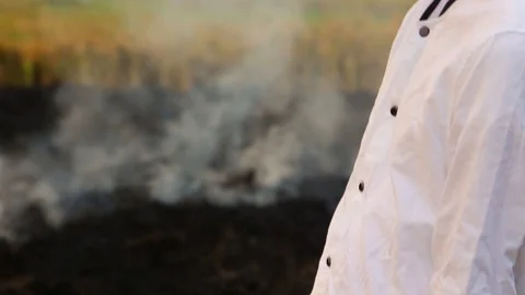 Man in white cloth looking to burning rice fields Stock Footage 90355463