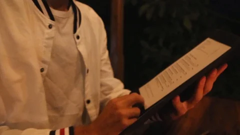Man in white cloth looking to menu in the restaurant Stock Footage 90355363