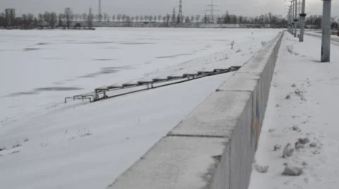 Man in white clothes climbing a dike of frozen water storage reservoir Stock Footage 45882810