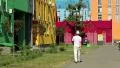 Man in white clothes walks down the street with manycoloured buildings HD Footage