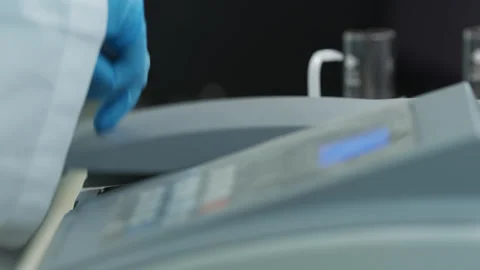 A man in a white coat and protective gloves works in a chemical laboratory with Stock Footage 333465863