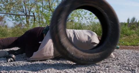Man in white coat falls on tiny pebbles against lush grass Stock Footage 249127410