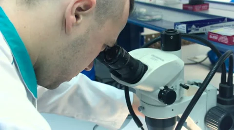 A Man in a White Coat Looking Into a Microscope in the Lab Closeup Video stock 60571165