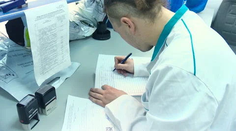 Man in a white coat makes notes about his research by hand in the laboratory Stock-Footage 59848433