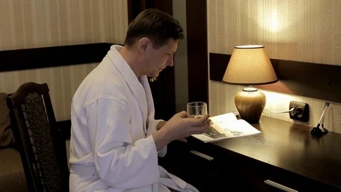 A man in a white coat sits in his office and leafs through a men's magazine Stock Footage 123745843