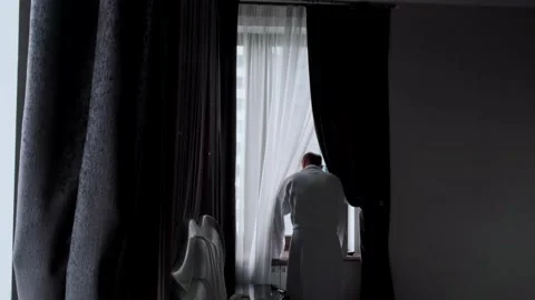 Man in a white coat stands by the window Stock Footage 145942998