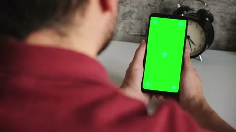 A man at a white Desk is sitting with a mobile phone in his hands with a green Stock Footage 141909573
