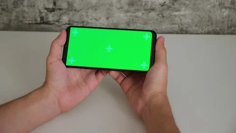 A man at a white Desk is sitting with a mobile phone in his hands with a green Stock Footage 141910191