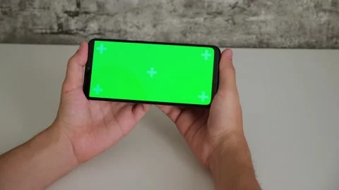 A man at a white Desk is sitting with a mobile phone in his hands with a green Stock Footage 146596205