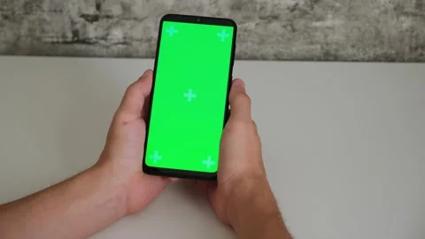 A man at a white Desk is sitting with a mobile phone in his hands with a green Stock Footage 147123635