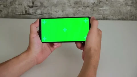 A man at a white Desk is sitting with a mobile phone in his hands with a green Stock Footage 156729014