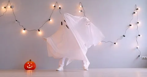 A man in a white ghost costume dances near a pumpkin Stock Footage 286207686