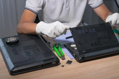 Man in white gloves disassembles laptop, disposal of dangerous battery power Stock Photos