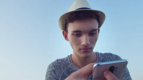Man in white hat holding mobile phone in front of him, reading message on social Stock Footage 314014630
