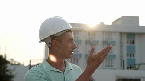 A man in a white helmet against the backdrop of a house with apartments Stock Footage 166392386