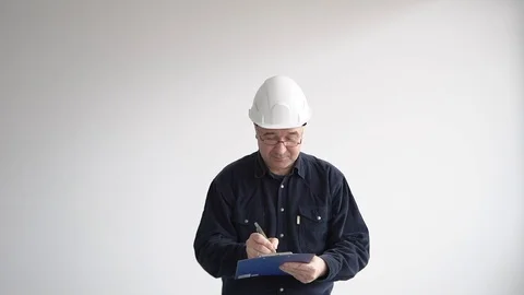 A man in a white helmet and a tablet in his hands. Writes with a pen and smiles Stock Footage 126232939