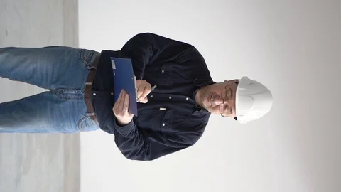 A man in a white helmet and a tablet in his hands. Writes with a pen Stock Footage 126233101