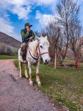 Man on White Horse Using Mobile Phone in Rural Kyrgyzstan Stockfoto's
