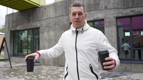 A man in a white jacket drinks coffee and has fun with friends, making faces Stock Footage 208862975