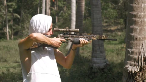 Man in white jacket is shooting from a crossbow Stock Footage 85805804