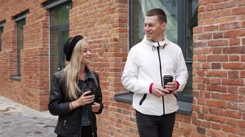 A man in a white jacket walks around the city with a young woman in a black hat Stock Footage 266772615