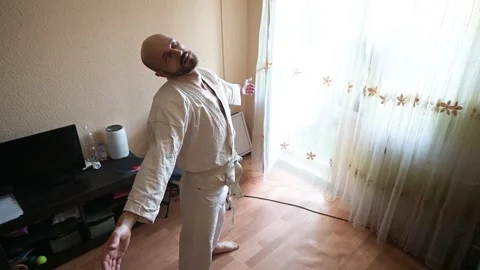 Man in White Karate Gi Practicing Breathing Exercises and Meditation at Home Stock Footage 342321588