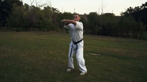 A man in White Kimono Practicing Kata Karate Early in the morning in the City Stock Footage 85441541