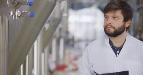 Man in white lab coat looking at equipment gauge and entering data in tablet Video stock 148391278