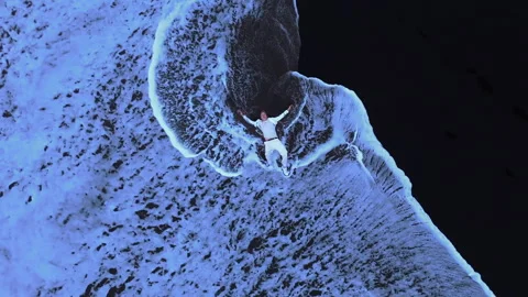 Man in white lying on the black sand beach and foaming waves hitting him Stock Footage 256100818