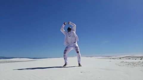 Man in White Performs Acrobatics with Color Powder in White Sand Desert Stock Footage 142340763