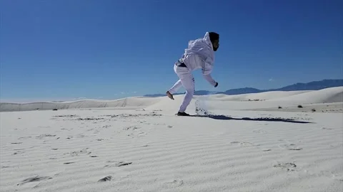 Man in White Performs Acrobatics in White Sand Desert with Color Powder Stock Footage 142340704