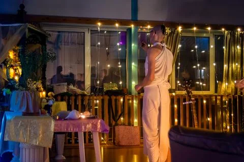 Man in white robe doing quiet ritual at dawn with candles and flowers Stock Photos