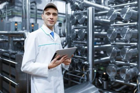 Man in a white robe with a tablet in his hands is in the production shop at the Stock Photos