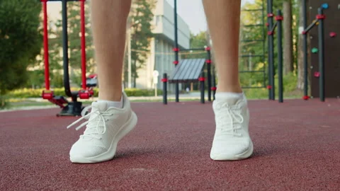 Man in white running sneakers doing warm up jumps on an outdoor sports grou.. Stock-Footage 341457592