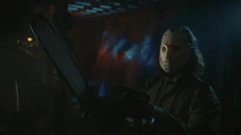 Man in the white scary mask standing in the warehouse and posing with a chainsaw Stock Footage 248058633