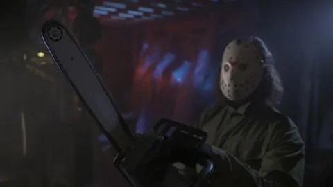 Man in the white scary mask standing in the warehouse and posing with a chainsaw Stock Footage 248119971