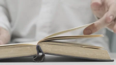 Man in white shirt flips through pages of old book or textbook 스톡 동영상 265879304