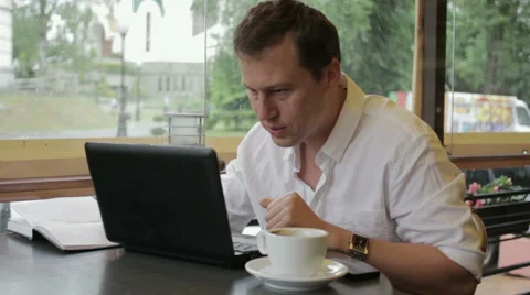 A man in a white shirt inspired by the work sitting in a summer cafe. He prints Stock Footage 68105528