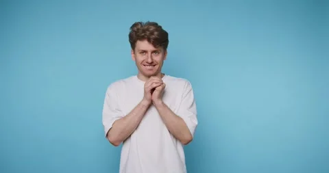 Man in white shirt with mischievous expression against blue background Stock Footage 315162327