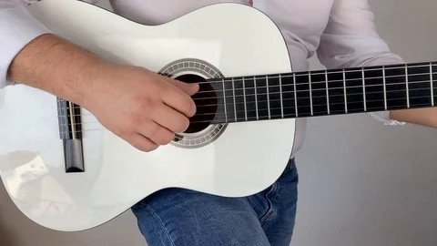 Man in white shirt plays six-string classical guitar at home, concept art Video stock 125884553