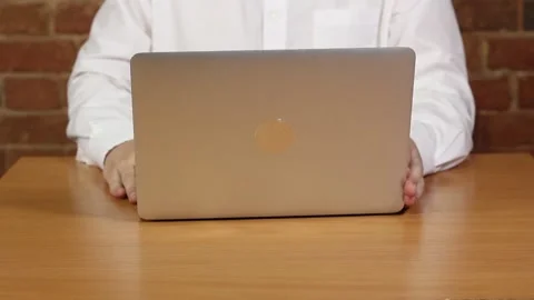 A man in a white shirt at a table in front of a laptop Stock Footage 132292143