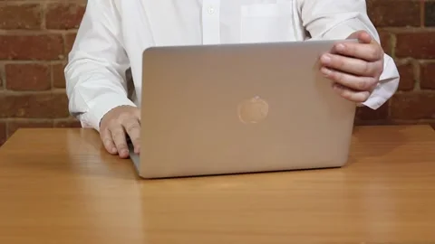 A man in a white shirt at a table in front of a laptop Stock Footage 132292163