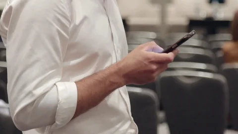 Man in a white shirt is typing something in his phone Stock Footage 76983227
