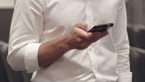 Man in a white shirt is typing something in his phone Stock Footage 76983305