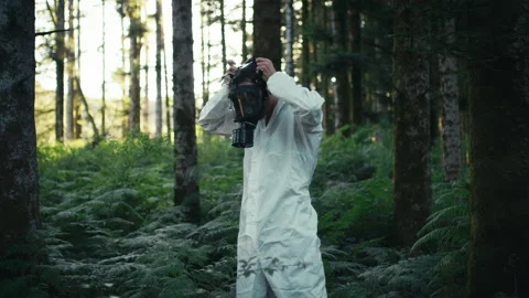 Man with white suit in the middle of the woods wears black gas mask Stock Footage 220502149