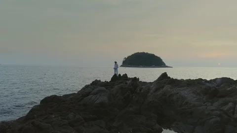 Man in white on sunset beach in Thailand rocks 库存影片 89842554