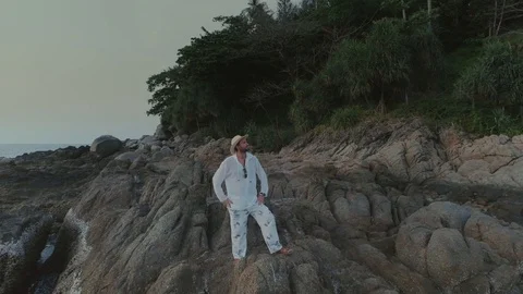 Man in white on sunset beach in Thailand rocks Stock-Footage 89842868