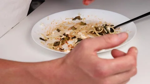 A man in a white T-shirt eats pasta with his hands. Stock Footage 281148882