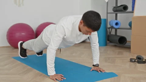 Man in white top doing pushup with hands on blue yoga mat and smartwatch vi.. Stock Footage 337431027